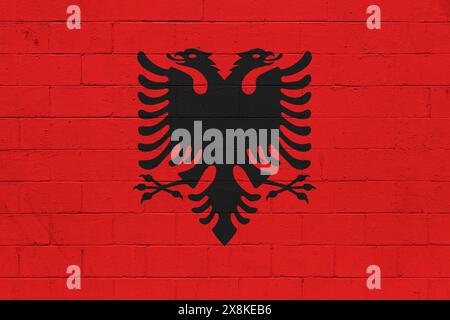 Die Flagge Albaniens ist auf einer Wand aus einem Schlackenblock gemalt. Stockfoto