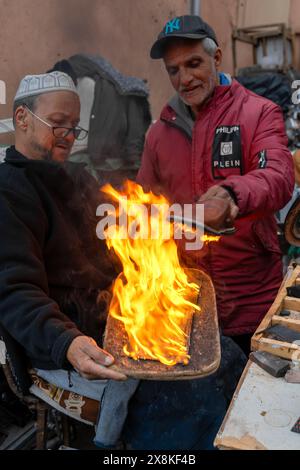 Marrakesch, Marokko - 23. März 2024: Traditionelle Schuhmacher im Souk der Medina von Marrakesch kleben neue Sohlen auf alte Schuhe Stockfoto