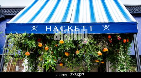 Blumengeschmückte blau-weiß gestreifte Markise des Hackett-Shops für die Chelsea in Bloom 2024 mit Pflanzen und Blumen Stockfoto