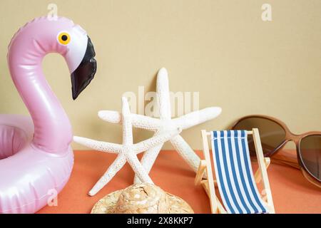 Sommerurlaub Strandkonzept. Sonnenliege, Seesterne, Strohhut, Sonnenbrille, Schwimmschlauch auf rotem und khakifarbenem Hintergrund Stockfoto