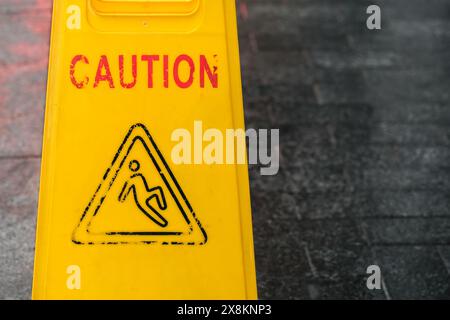 Nahaufnahme eines abgenutzten Warnschilds für nassen Boden. Stockfoto