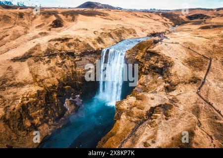 Aus der Vogelperspektive des majestätischen mächtigen Skogafoss-Wasserfalls, der im Herbst im Süden Islands von einer Klippe zwischen trockenen Bergen fließt Stockfoto