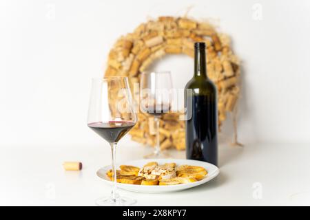 Gläser Wein mit Brie-Käse und geröstetem Brot vor dem Hintergrund eines Kranzes aus Weinkorken. Weißer Hintergrund, ausgewählter Fokus. Hochwertiges Foto Stockfoto