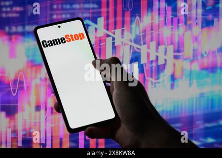 Brüssel, Belgien Mai 2024. Das GameStop-Logo wird auf einem Smartphone mit einer Bestandsgrafik angezeigt, die auf dem Bildschirm im Hintergrund in dieser Fotoabbildung sichtbar ist. Aufgenommen in Brüssel, Belgien. Am 25. Mai 2024. (Jonathan Raa/SIPA USA) *** ausschließlich für redaktionelle Nachrichten *** Credit: SIPA USA/Alamy Live News Stockfoto