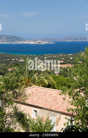 Lumio, Haute-Corse, Korsika, Frankreich. Blick über die gekachelte Dachterrasse über landwirtschaftliche Flächen bis zum einladenden blauen Wasser des Golfs von Calvi. Stockfoto