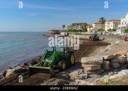 Bulldozer reinigen den Strand von toten Algen vor dem Touristenhafen San Vincenzo, Toskana, Italien Stockfoto