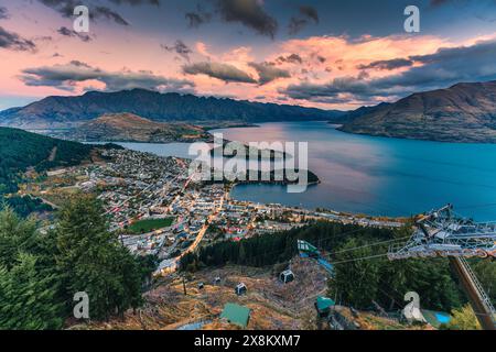 Blick aus der Vogelperspektive auf den wunderschönen Sonnenuntergang über dem beleuchteten Queenstown mit Lake Wakatipu und Skyline Gondel in Neuseeland Stockfoto