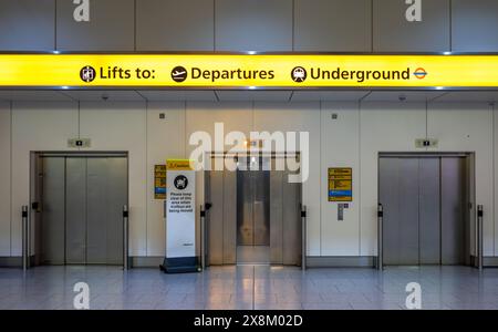 Drei Lifte oder Aufzüge, die zu Abfahrten und Londoner U-Bahn-Zügen in der Ankunftshalle des Terminals 4 am Flughafen Heathrow, London UK, führen. Stockfoto