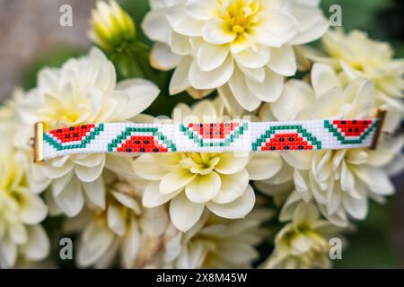 Sommer-Vibes: Perlenbesetztes Armband mit Wassermelonenscheiben auf Blumen. DIY- und Bastelkonzept Stockfoto
