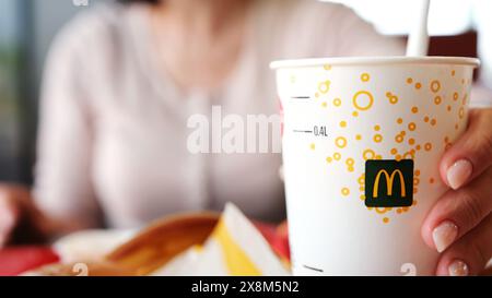 Poznan, Polen - 28. april 2024: Lady schlürft gekühltes alkoholfreies Getränk im McDonald's Fast Food Joint Stockfoto