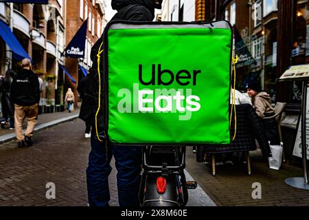 Haag, Niederlande - 9. April 2023: Big Green Uber Eats Food Bag. Essenslieferant mit dem Fahrrad Stockfoto
