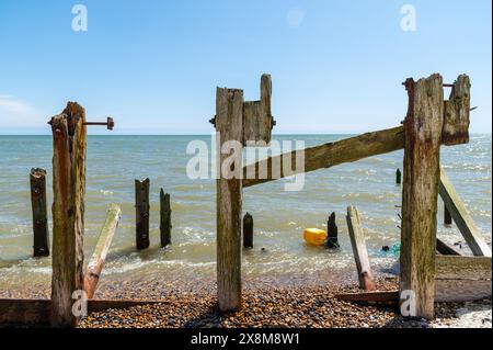 Drei alte und kaputte hölzerne Schutzmauern, beschädigte Groyne Pfosten, beschädigte Mole im Rye Harbour Nature Reserve an einem sonnigen Tag Stockfoto