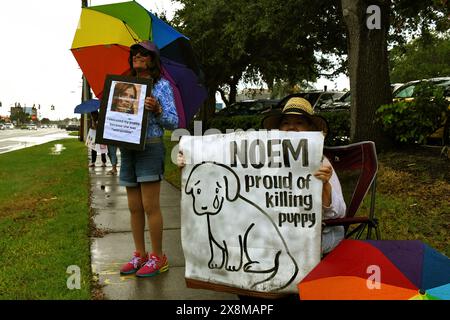 Cape Canaveral, Brevard County, Florida, USA. Mai 2024. Demonstranten halten Schilder gegenüber vom Radisson Resort, um gegen den Gastsprecher des Brevard Republican Executive Committee, Kristi Noem, zu protestieren. Noem gibt öffentlich zu, ihren Hund „Cricket“ erschossen zu haben, weil er „nicht trainierbar“ war. "Nein zu Noem" aus einem Bullhorn und "Wer lass die Hunde raus" aus dem Lautsprechersystem. Quelle: Julian Leek/Alamy Live News Stockfoto