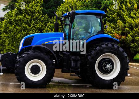 Die neuen blauen landwirtschaftlichen Traktoren verschiedener Modelle stehen auf dem Messegelände in Reihe, um den Beginn der Frühjahrssaat von landwirtschaftlichen Maschinen zu beginnen Stockfoto