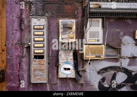 Eine grungy Wand mit verwitterten Gegensprechanlagen und beschädigtem Postfach, die urbanen Verfall und Vernachlässigung in einer städtischen Umgebung zum Ausdruck bringt. Stockfoto