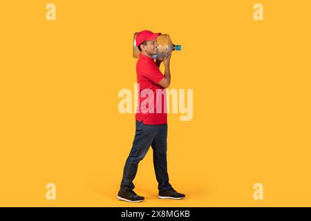 Mann mit Wasser Gallone vor gelbem Hintergrund in Studio-Einstellung Stockfoto