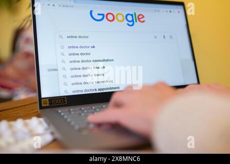 Person, die auf einem Laptop nach britischen Online-Arztdiensten sucht und Suchvorschläge auf Google anzeigt. Stockfoto