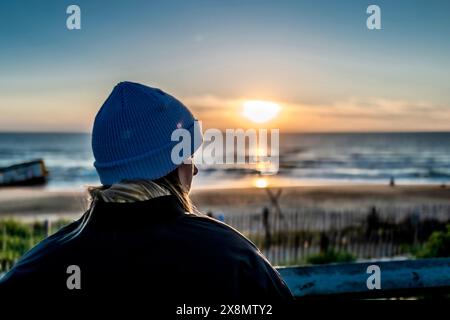 Frau am Strand, die den Sonnenuntergang beobachtet Stockfoto