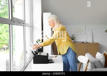 Reife Frau, die zu Hause Drucker benutzt Stockfoto