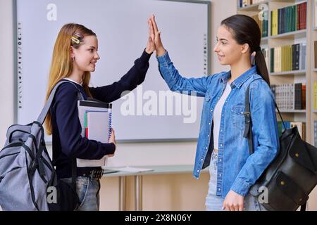 Teenager-Studentinnen grüßen High Fiving mit Händen im Bibliothekskurs Stockfoto