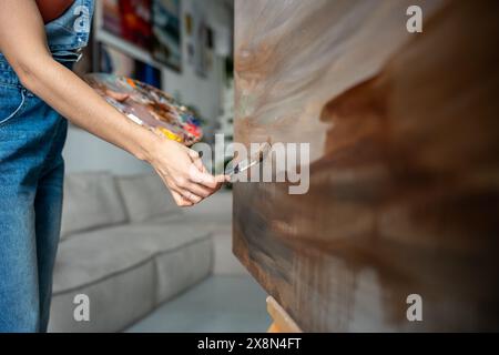 Nahaufnahme einer Künstlerin, die mit behutsamen, sanften Pinselstrichen an abstrakter Malerei arbeitet Stockfoto