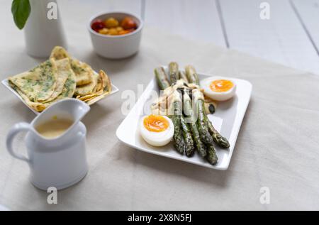 Grüner Spargel serviert mit gekochten Eiern. Spargel ist in Deutschland während der Spargelzeit als Quelle für Ballaststoffe sehr beliebt Stockfoto