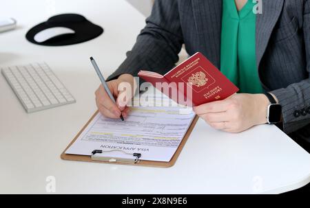 Nahaufnahme einer Frau, die Dokumente für den Visumantrag mit einem russischen Reisepass ausfüllt Stockfoto