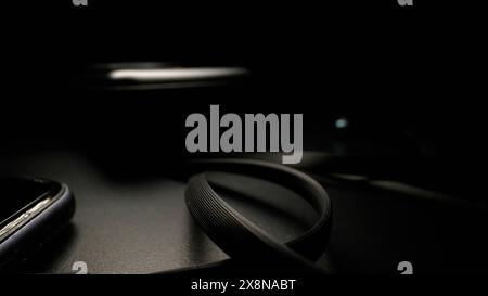 Smartphone-Kabel vom Ladegerät auf dem Tisch auf schwarzem Hintergrund. Kabel vom Ladegerät zum Telefon auf schwarzem Hintergrund in Nahaufnahme. Stockfoto