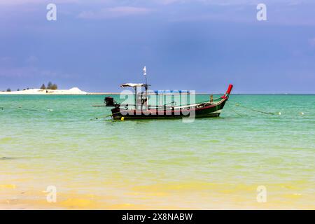 Traditionelles thailändisches Longtail-Boot, das in einem flachen tropischen Ozean in Khao Lak, Thailand, verankert ist Stockfoto