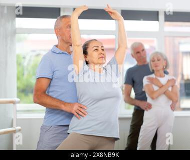 Reife Frau übt Ballettpositionen zu zweit mit Mann im Tanzstudio aus Stockfoto