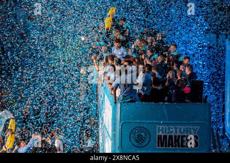 Manchester, Großbritannien. Mai 2024. Jeremy Doku mit der Trophäe des Premierministers, die von Ruben Dias beobachtet wird, während die Siegesparade von Manchester City entlang Deansgate im Stadtzentrum zieht. Fans säumten die Strecke im Stadtzentrum, um die Parade zu sehen, um den historischen Triumph ihres Vereins in der Premier League zu feiern. Manchester City war die erste Mannschaft in der Geschichte des englischen Fußballs, die vier Titel in der Liga gewann, dank eines Sieges 3-1 gegen West Ham United am vergangenen Sonntag (19. Mai). Manchester UK Bild: Garyroberts/worldwidefeatures.com Credit: GaryRobertsphotography/Alamy Live News Stockfoto