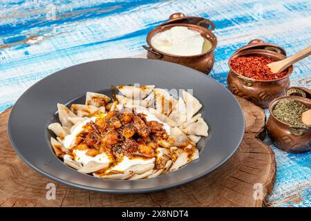 Manti ist ein türkisches Essen. Ravioli Manti Mahlzeit auf einem Holzhintergrund aus türkischer Küche zum Mittagessen essen Sie Gericht mit Tomatensoße auf einem Teller. Stockfoto