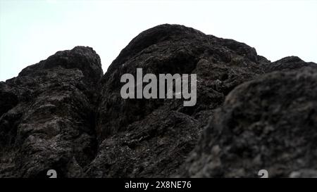 Riesige Felsen auf bewölktem Himmel Hintergrund. Clip. Nahaufnahme der grauen Steinstruktur. Stockfoto