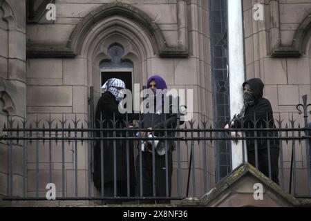 Manchester, England, Großbritannien. Mai 2024. Schüler, deren Gesichter bedeckt sind, gehen auf den Balkon des Whitworth Building. Eine Gruppe von Studenten besetzte und verbarrikadierte sich im Whitworth-Gebäude auf dem Campus der University of Manchester. Die Studenten besetzten das Gebäude wegen Israels anhaltendem Völkermord in Gaza und der Komplizenschaft der Universität daran. Diese Aktion fällt mit dem Zelt des Widerstands für Palästina zusammen, das in den letzten 25 Tagen gegenüber existierte. Quelle: ZUMA Press, Inc./Alamy Live News Stockfoto