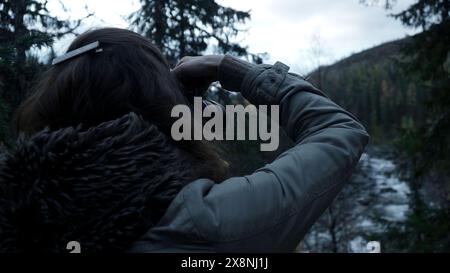 Eine Frau mit Kamera fotografiert einen Wald im Nebel. Clip. Herbstlandschaft und bewaldete Hänge. Stockfoto