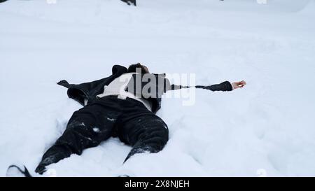 Glücklicher junger Mann im märchenhaften Winterwald, der auf Schnee liegt. Medien. Religionsbegriff und das Gefühl der Einheit mit der Natur. Stockfoto