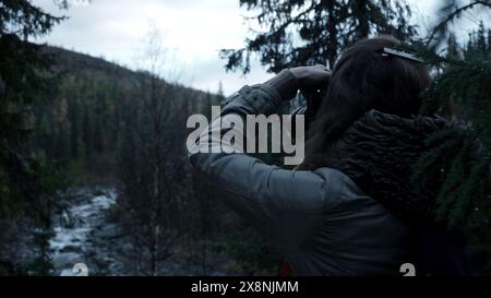 Eine Frau mit Kamera fotografiert einen Wald im Nebel. Clip. Herbstlandschaft und bewaldete Hänge. Stockfoto