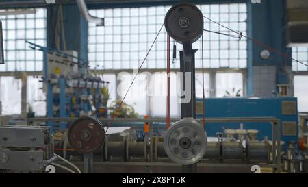 Industriemaschine mit rotierenden Spulen und Draht. Kreativ. Industrielle Wicklung von Drähten und Kabeln an Werkzeugmaschinen. Automatisierte Maschinen mit Spulen Stockfoto