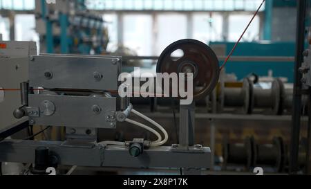 Kabelproduktionsprozess, Mechanismus in einer Kabelfabrik. Kreativ. Industrieller Hintergrund mit Spinnspulen. Stockfoto