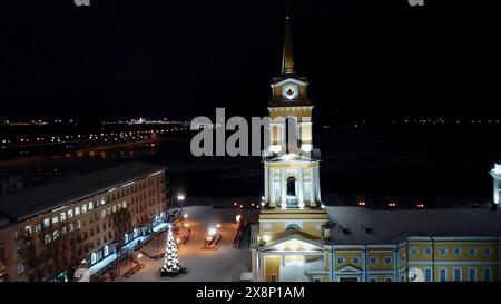 Aus der Vogelperspektive auf die beleuchtete Kirche und die Wohngebäude. Clip. Wunderschöne Stadt bei Nacht. Stockfoto