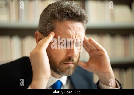 Nahporträt eines gestressten Mannes mit Kopfschmerzen Migräne. Müder Mann fühlt Schmerzen in der Hand Brille, die trockene, gereizte Augen reizt, müde von der Computerarbeit, Stockfoto