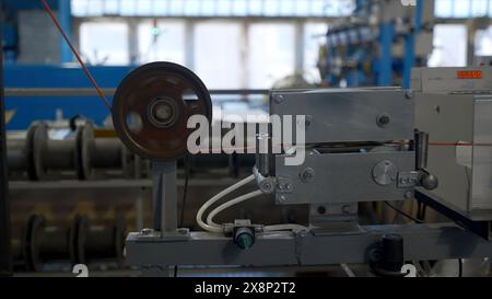 Kabelproduktionsprozess, Mechanismus in einer Kabelfabrik. Kreativ. Industrieller Hintergrund mit Spinnspulen. Stockfoto