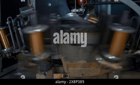 Spulen mit Kupferdraht drehen sich an der Maschine. Kreativ. Rotierende Spulen aus Kupferdraht an Industriemaschinen. Metallurgische Anlage mit automatisierten Anlagen Stockfoto