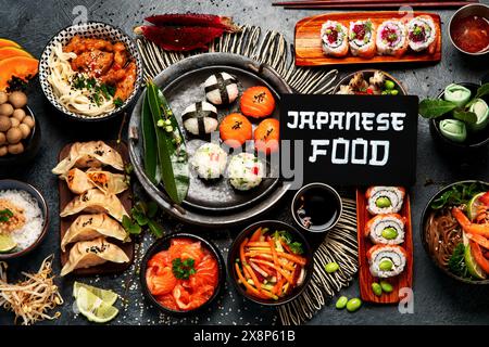 Sushi und japanisches Essen auf dunklem Hintergrund. Sushi-Brötchen, Suppe, gebratener Reis, Nigiri, Sojasauce, Stäbchen. Asiatisch-japanisches Essen. Draufsicht. Stockfoto