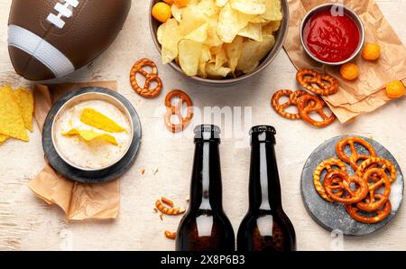 Snacks zum Anschauen eines American Football-Spiels. Bier, Chips, Brezeln, Soße auf hölzernem Hintergrund. Draufsicht Stockfoto