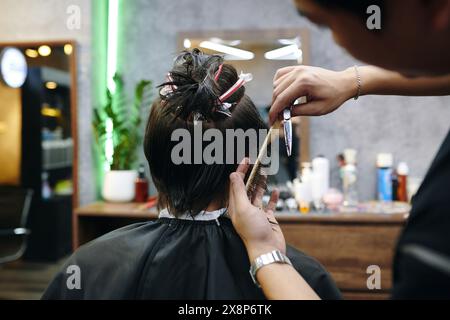 Junger Mann, der als Friseur im Friseursalon arbeitet Stockfoto