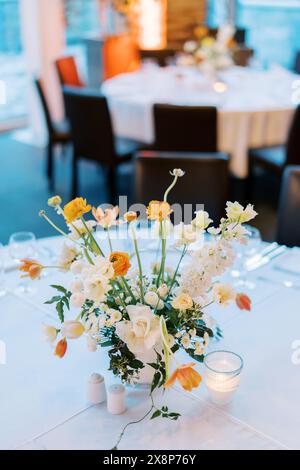 Farbenfroher Blumenstrauß steht neben Kerzen auf einem festlichen Tisch Stockfoto