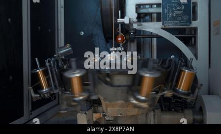 Spulen mit Kupferdraht drehen sich an der Maschine. Kreativ. Rotierende Spulen aus Kupferdraht an Industriemaschinen. Metallurgische Anlage mit automatisierten Anlagen Stockfoto