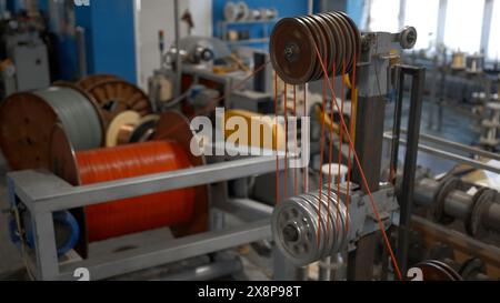 Rotierende Industriemaschine mit Spulen und Drähten. Kreativ. Werkstatt im Industriewerk mit Spinnmaschinen. Stockfoto