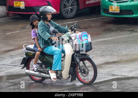 SAMUT PRAKAN, THAILAND, 20. März 2024, Eine Frau und ein Mädchen fahren im Regen Motorrad Stockfoto